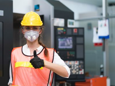 ingeniero mujer con protección de seguridad, levantando pulgar dentro de planta industrial